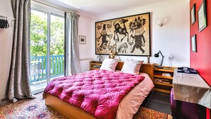 A bedroom with a large bed, a balcony, a painting, and a small table. - Chambre d'Hôtes Txori Etxea (Arcangues)