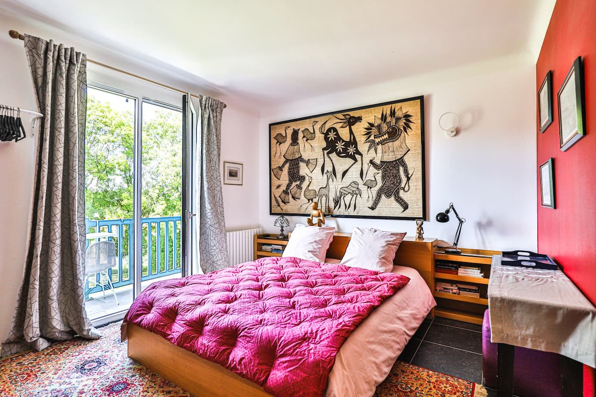 Ein Schlafzimmer mit einem großen Bett, einem Balkon, einem Gemälde und einem kleinen Tisch.