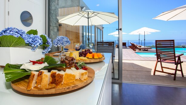 A terrace with a pool, wooden chairs, and umbrellas.