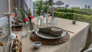 A table set for a meal with candles, a view of the sea, and a sunset.