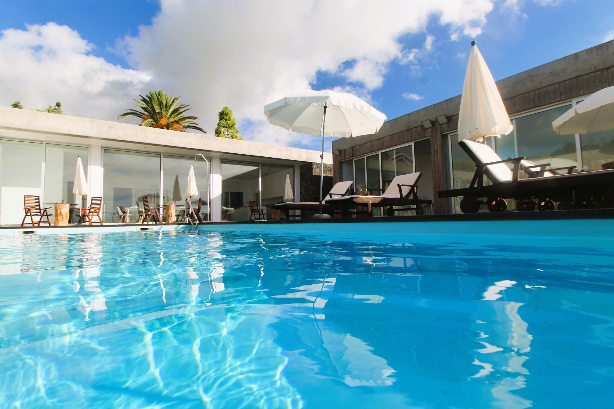 A swimming pool with lounge chairs and umbrellas, surrounded by modern architecture.