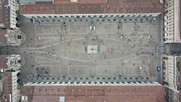 Eine Vogelperspektive auf einen Platz mit einem zentralen Denkmal, umliegenden Gebäuden und einem Parkbereich.
