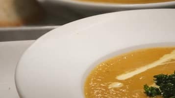 Un tazón blanco de sopa con un adorno sobre una bandeja.