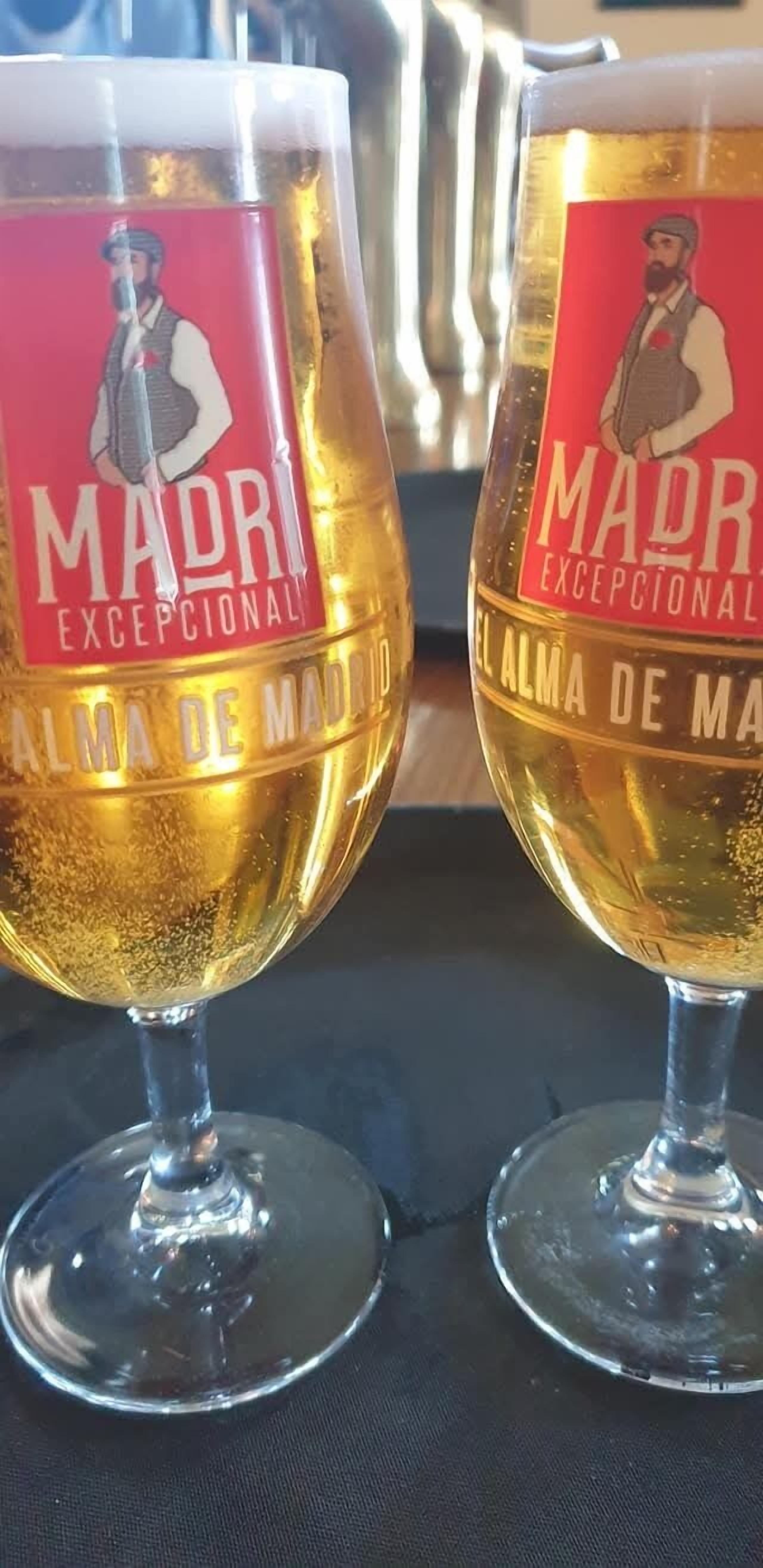 Two glasses of beer with labels reading "Madrid Excepcional" and "El Alma de Madrid."
