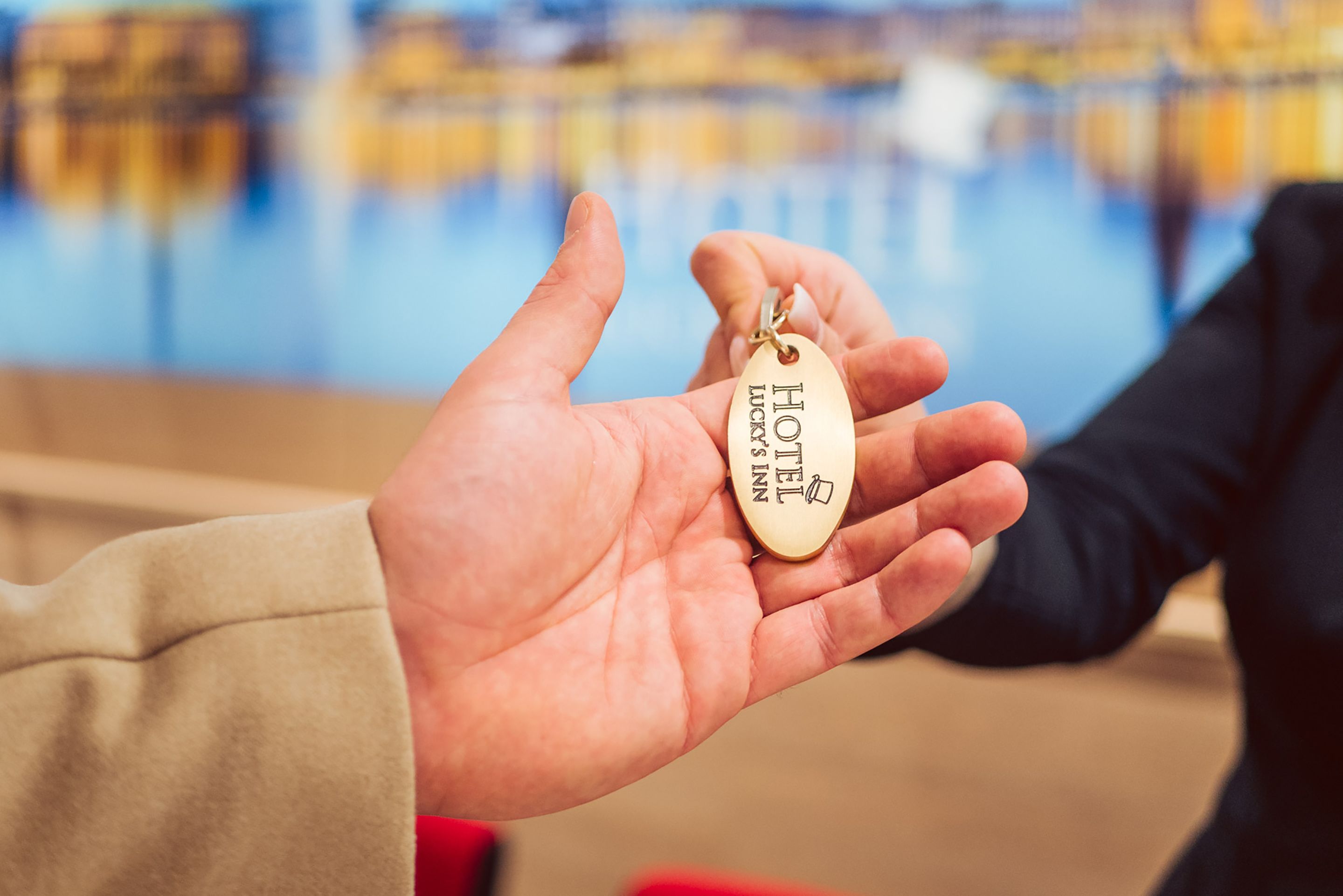 A hand holding a key tag with the inscription "HOTEL LUCKY".
