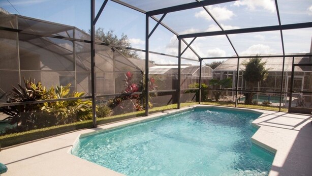 A rectangular pool with a clear blue water surface, surrounded by a covered area with a metal frame and mesh sides. - Ly58134 - Indian Ridge - 4 Bed 2 Baths Villa (Kissimmee)