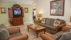 A living room with a sofa, armchairs, a coffee table, a TV, and a framed picture on the wall. - Ly58134 - Indian Ridge - 4 Bed 2 Baths Villa (Kissimmee)