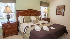 A neatly arranged bedroom with a large bed, two bedside tables, and a nightstand. - Ly58134 - Indian Ridge - 4 Bed 2 Baths Villa (Kissimmee)