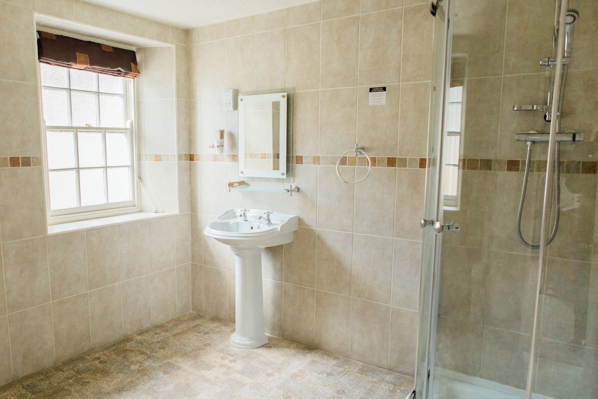 Ein Badezimmer mit einem Standwaschbecken, einer Duschkabine aus Glas und einem Fenster mit Blick.