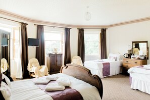 Een hotelkamer met twee bedden, een bureau, een stoel, een televisie en een raam.