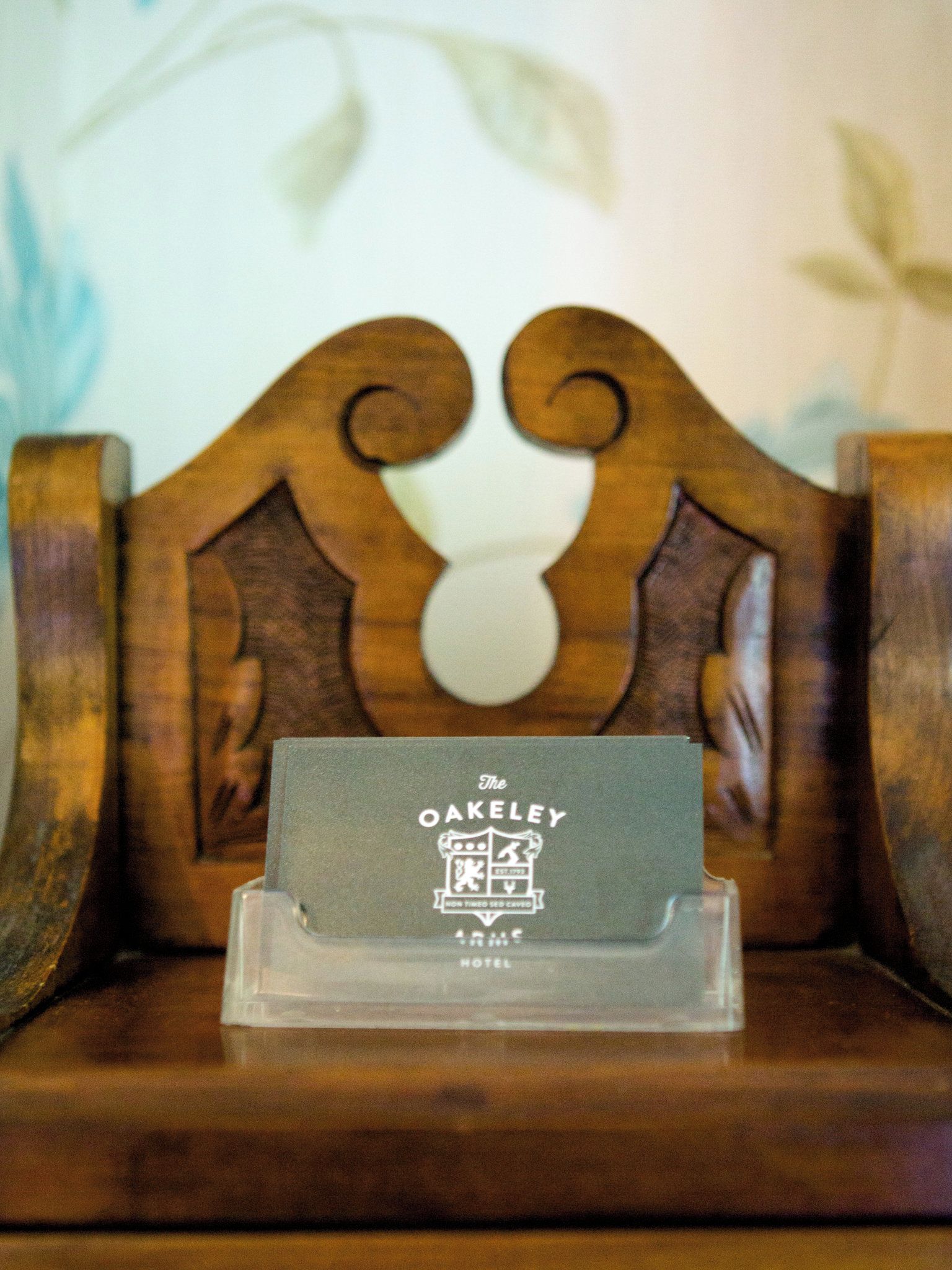 A wooden chair with a carved backrest and a business card holder in front.