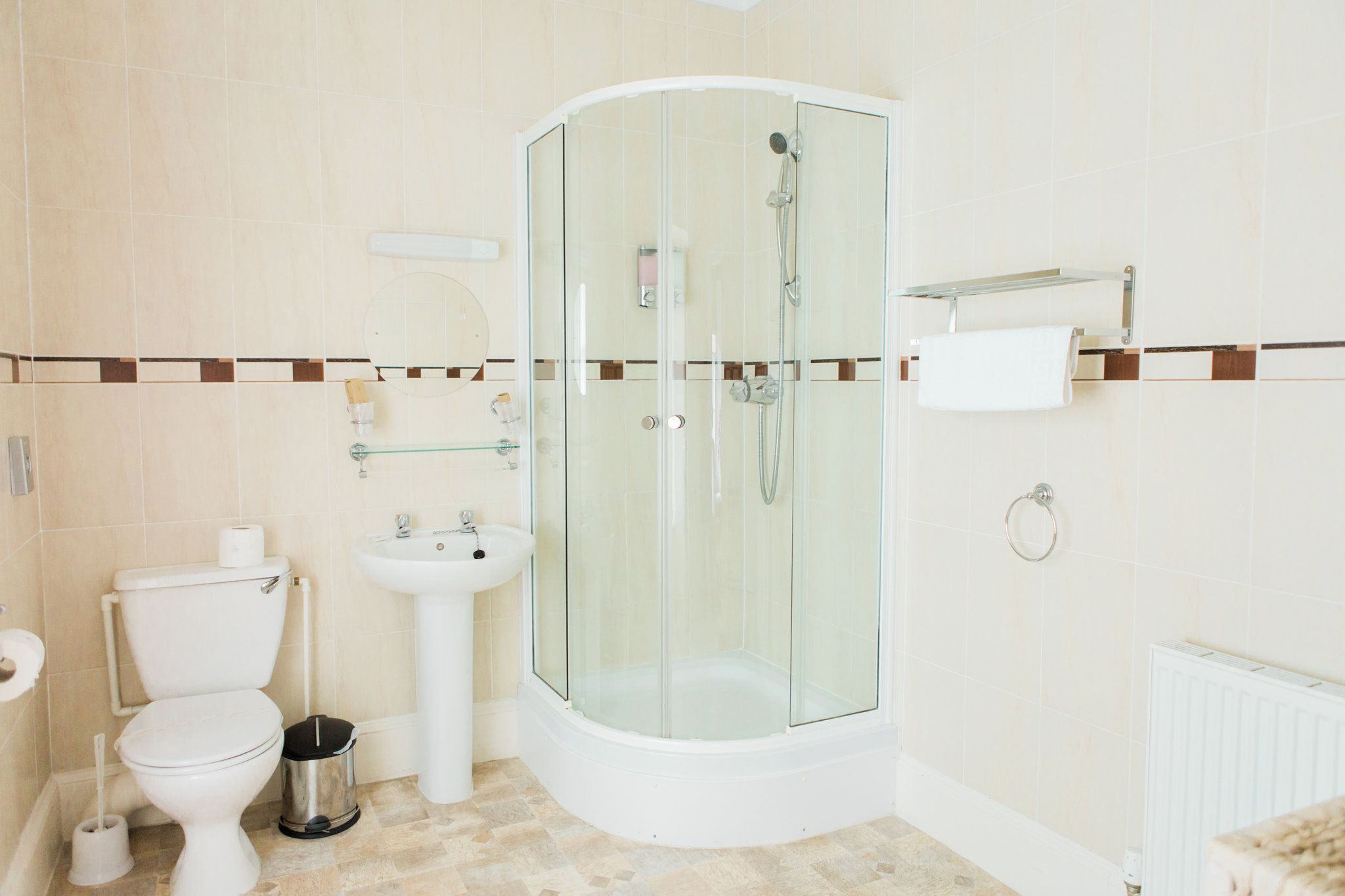 Un baño moderno con ducha de vidrio, inodoro, lavamanos y barra para toallas.