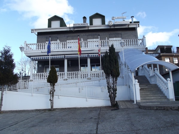 A two-story building with a balcony, a staircase, and flags. - La Montaña Palentina (Guardo)