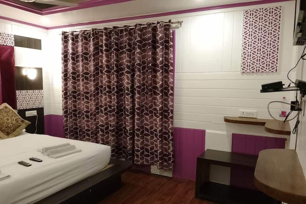 Quarto com cama, área de chuveiro, penteadeira e prateleira na parede.