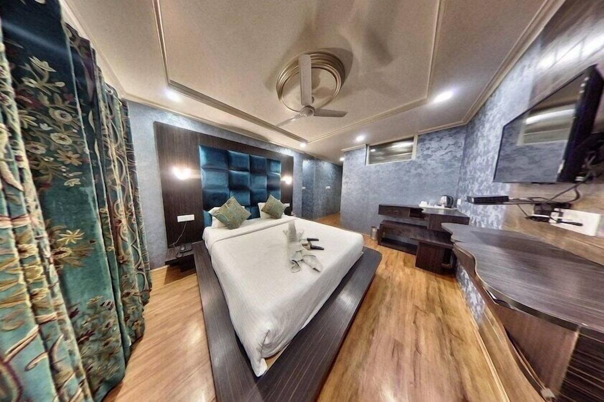 Quarto de hotel moderno com cama, televisão, escrivaninha e banheiro.