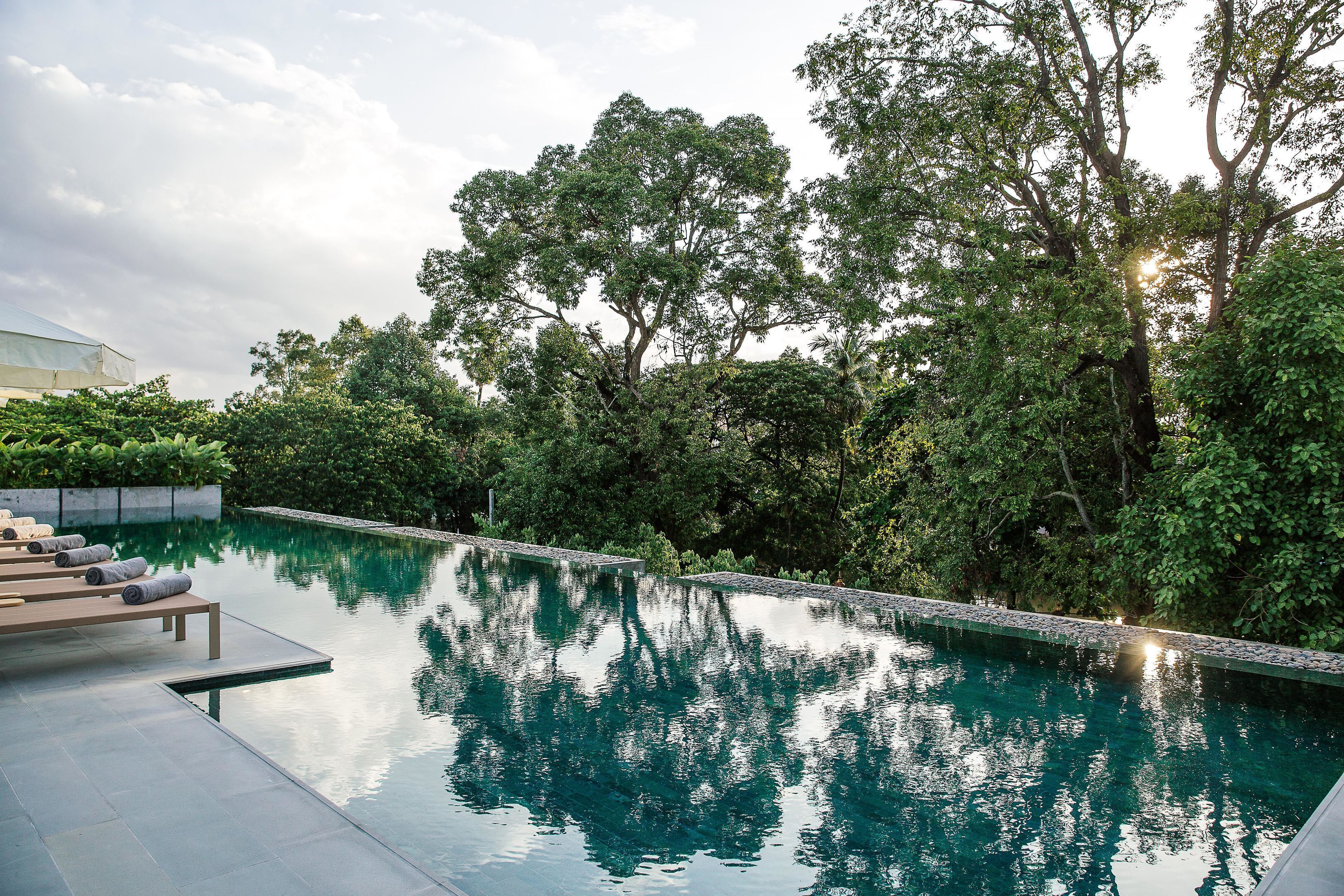 Una piscina al aire libre, sombrillas, sillones reclinables de piscina
