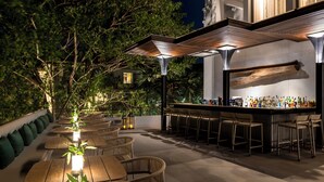 An outdoor bar area with multiple seating arrangements and a bar counter. - Treeline Urban Resort (Siem Reap)
