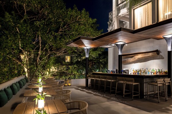 An outdoor bar area with multiple seating arrangements and a bar counter. - Treeline Urban Resort (Siem Reap)