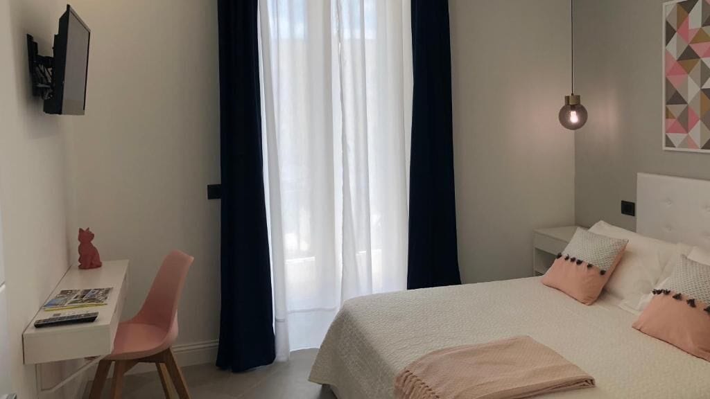 A bedroom with a bed, bedside table, and a desk with a chair.