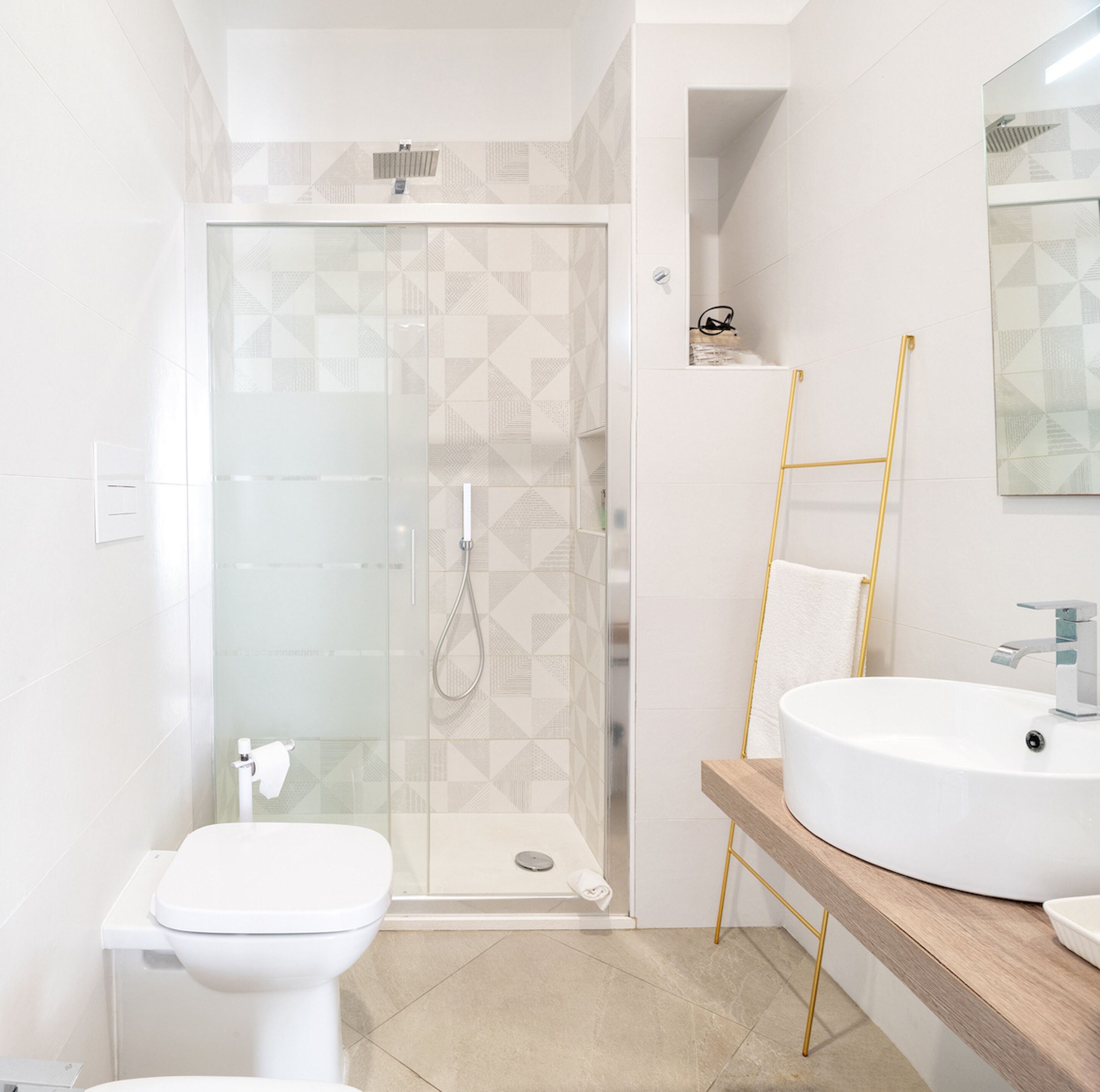 Une salle de bain moderne avec une douche à parois de verre, des toilettes blanches et un meuble-lavabo en bois avec un évier.
