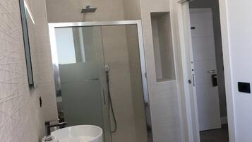 A bathroom with a glass-enclosed shower, a white sink, and a mirror.