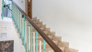 A staircase with wooden handrails and teal accents, leading to a door with a small potted plant beside it. - B&B Spigolehouse (Syracuse)