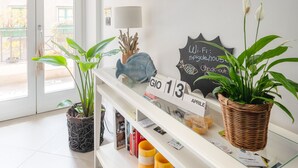 A reception area with a white console table, framed artwork, a Wi-Fi sign, a calendar, and potted plants. - B&B Spigolehouse (Syracuse)
