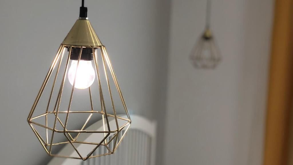 Un luminaire suspendu de forme géométrique, avec une ampoule visible.