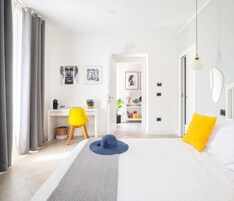 Un dormitorio moderno con una cama, un escritorio y una silla. Hay cuadros en la pared.