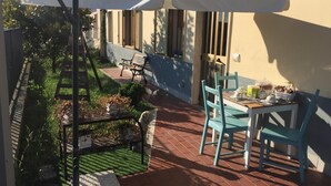 A patio with a table and chairs, a white umbrella, and a bench. - B&B San Lorenzo (Benevento)