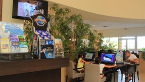 A reception area with a counter displaying various travel guides and a television screen. There are several people seated at tables with laptops. - Ly86465 - Encantada Resort - 2 Bed 2 Baths Townhome (Kissimmee)