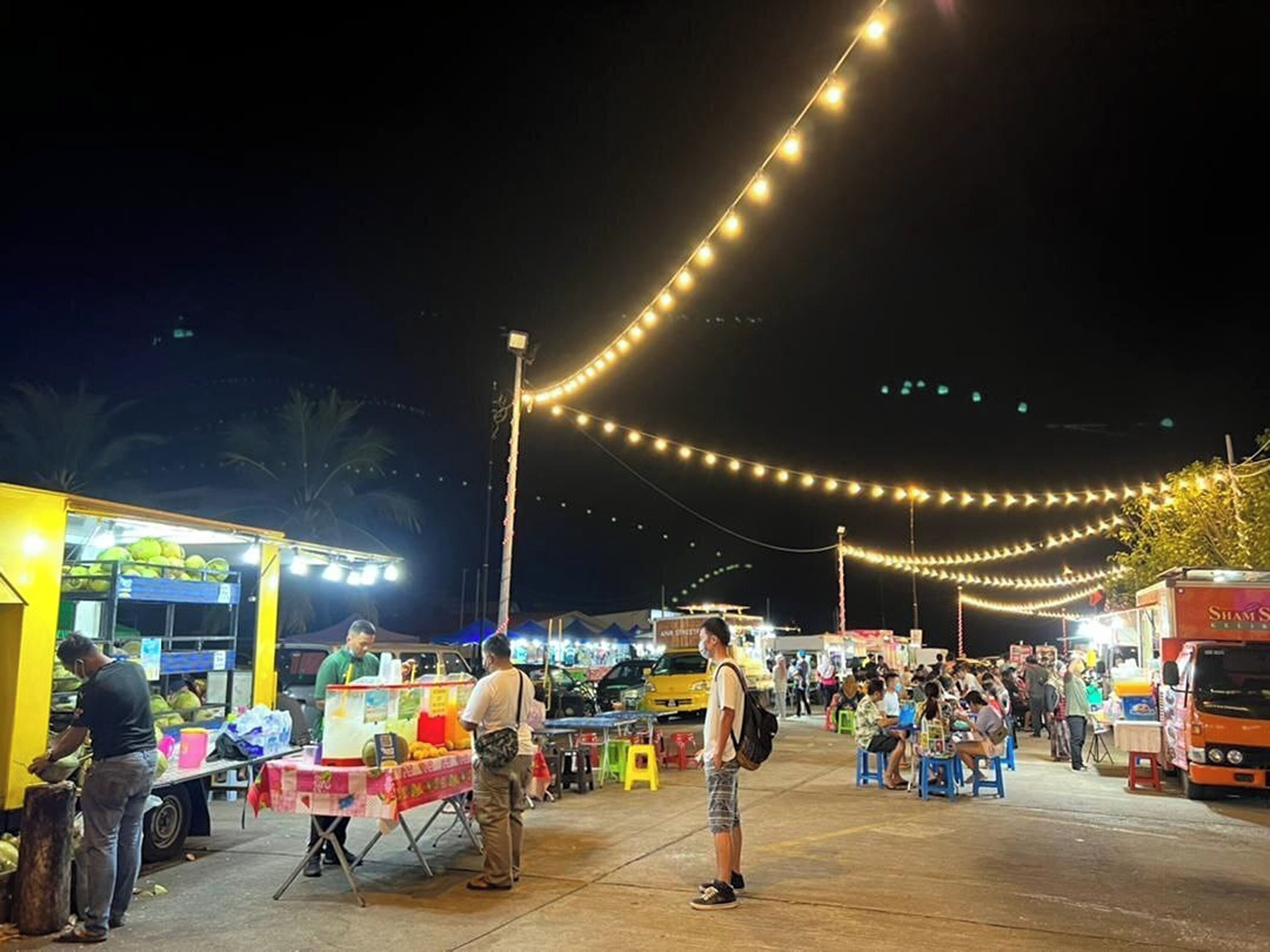 A bustling outdoor market with various stalls and people.