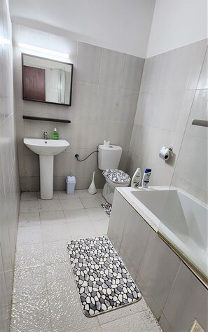 A small bathroom with a sink, toilet, and bathtub. - VMD Aparthôtel (Abidjan)
