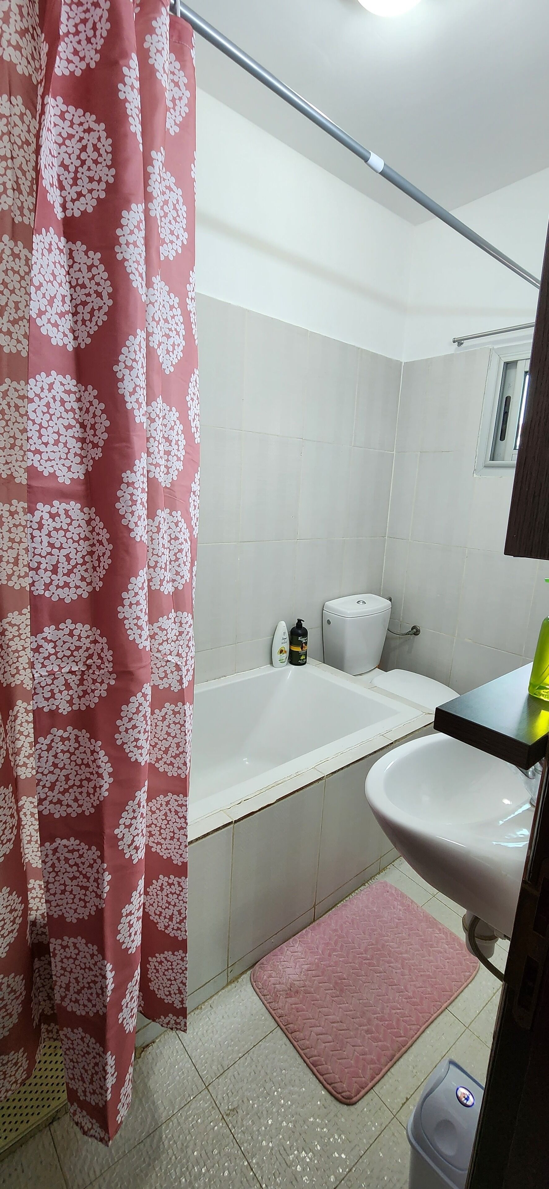 A bathroom with a shower curtain, a bathtub, a toilet, and a sink.