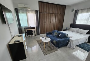 A modern bedroom with a bed, a desk, a chair, and a TV. - VMD Aparthôtel (Abidjan)