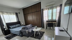 A modern bedroom with a bed, a desk, a chair, a wardrobe, and a TV. - VMD Aparthôtel (Abidjan)