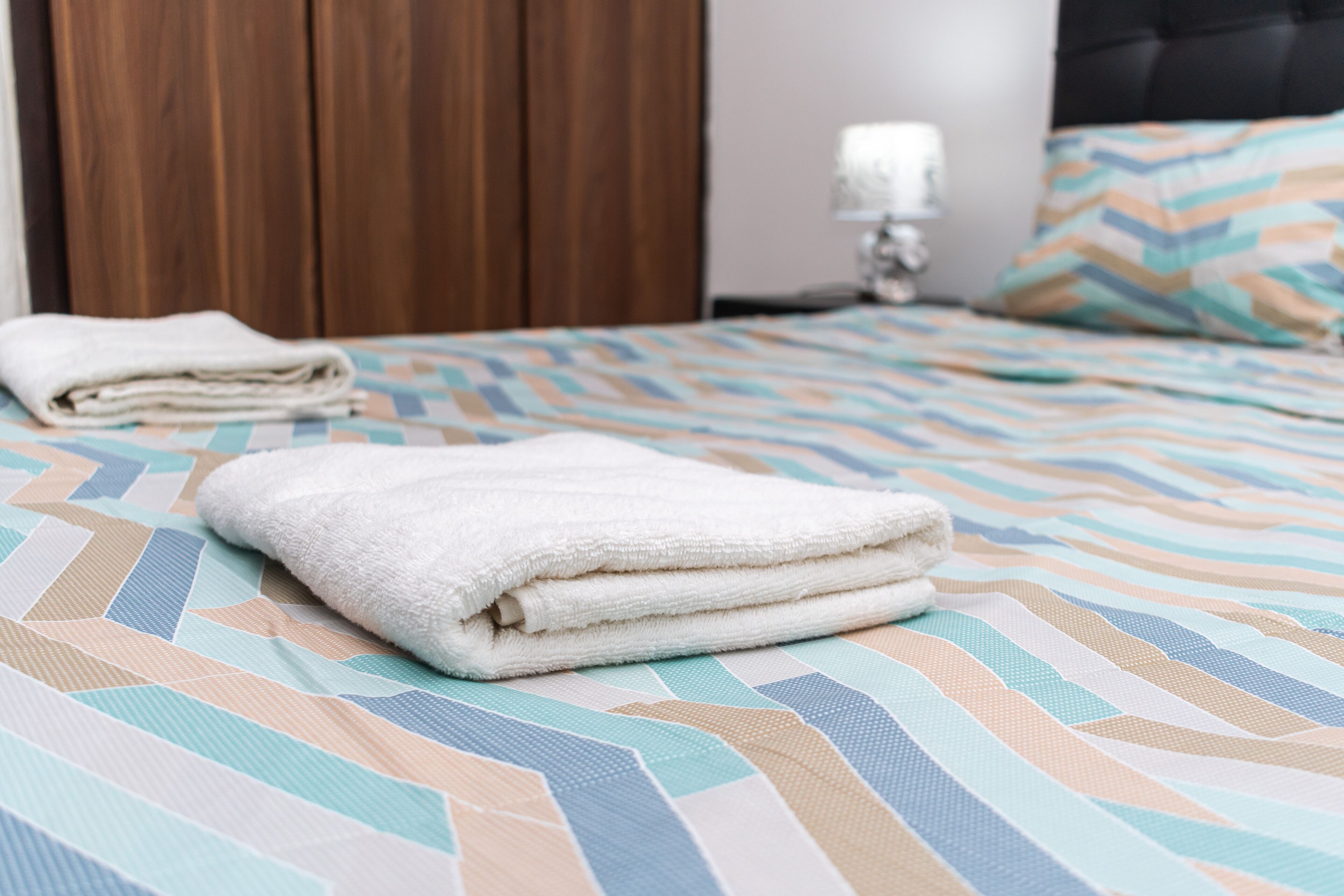 Un lit bien fait, avec une couvre-lit à rayures et une serviette blanche pliée posée dessus.