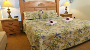 Una cama bien hecha con ropa de cama floral, dos lámparas de noche y un cabecero de madera.