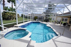Una piscina coperta con una vasca idromassaggio, circondata da palme e da una zona prendisole.