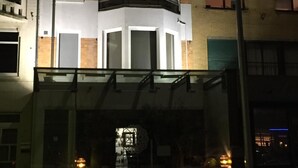 A modern building with a glass entrance, a balcony, and a car parked in front. - App De Panne (De Panne)