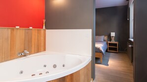 A modern bathroom with a freestanding bathtub, wooden paneling, and a red accent wall. - App De Panne (De Panne)