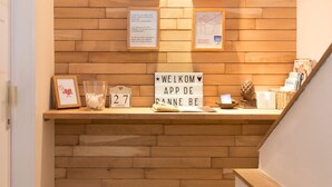 A reception area with a wooden wall, a welcome sign, and a counter with various items. - App De Panne (De Panne)