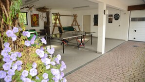 A room with a ping pong table, a green chair, and a wooden swing set. - Hotel Leise Garni Willingen (Willingen)