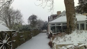 A snow-covered pathway leading to a building with a glass conservatory. - Shiralee Bed & Breakfast (Salisbury)