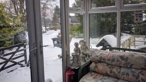 A conservatory with large windows, a floral sofa, and a fire extinguisher. - Shiralee Bed & Breakfast (Salisbury)