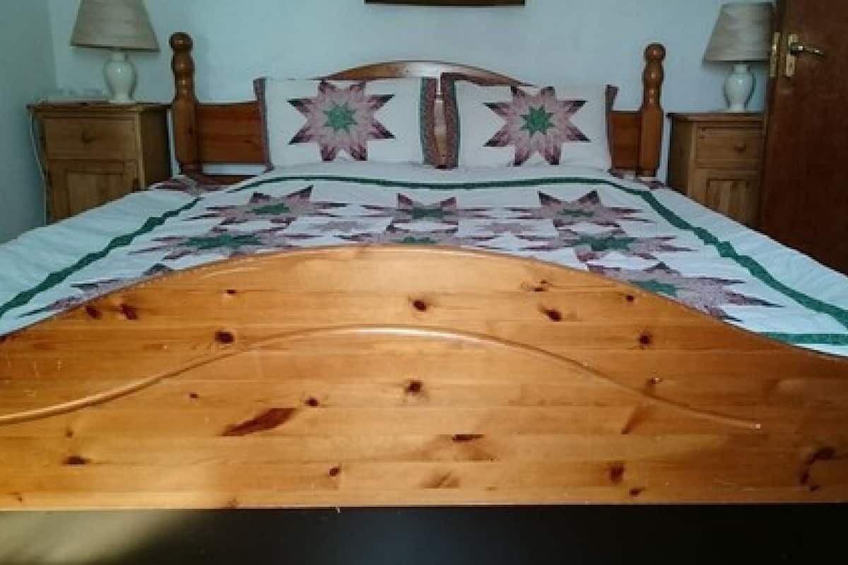 A wooden bed with a headboard, two nightstands, and a quilt.