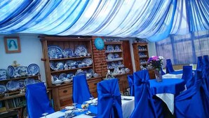A dining area with blue chairs, a table set for a meal, and shelves of blue and white plates. - Shiralee Bed & Breakfast (Salisbury)