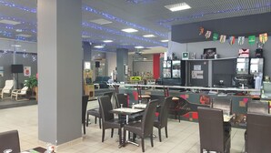 A restaurant with tables and chairs, a counter, and a ceiling with blue lights.