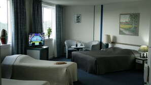 A hotel room with two beds, a TV, a small table, and a chair.