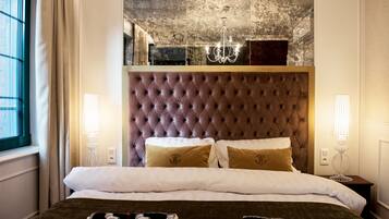A neatly made bed with a tufted headboard, two bedside lamps, and a large window with curtains.